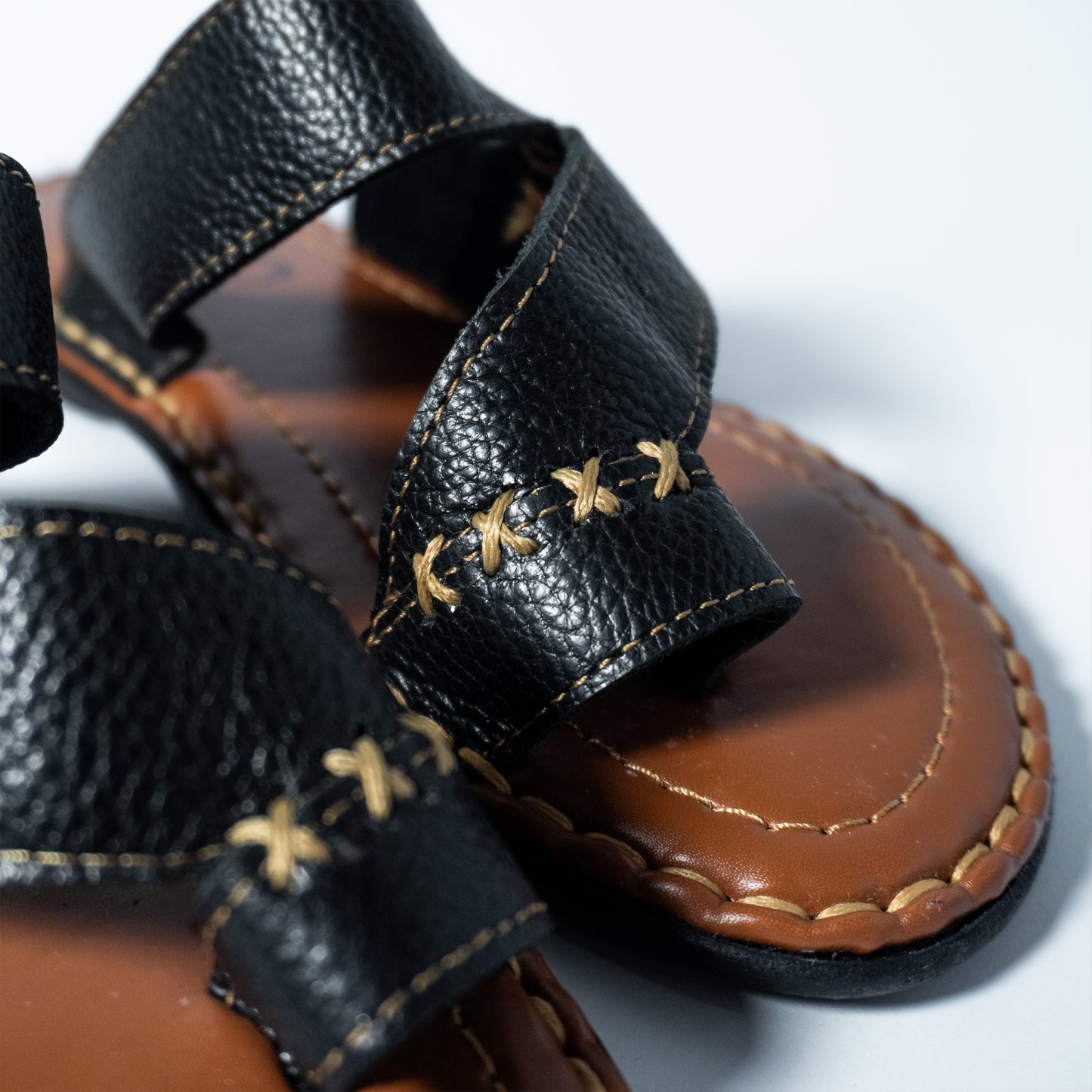 Close-up of black leather sandals with brown soles on a white background