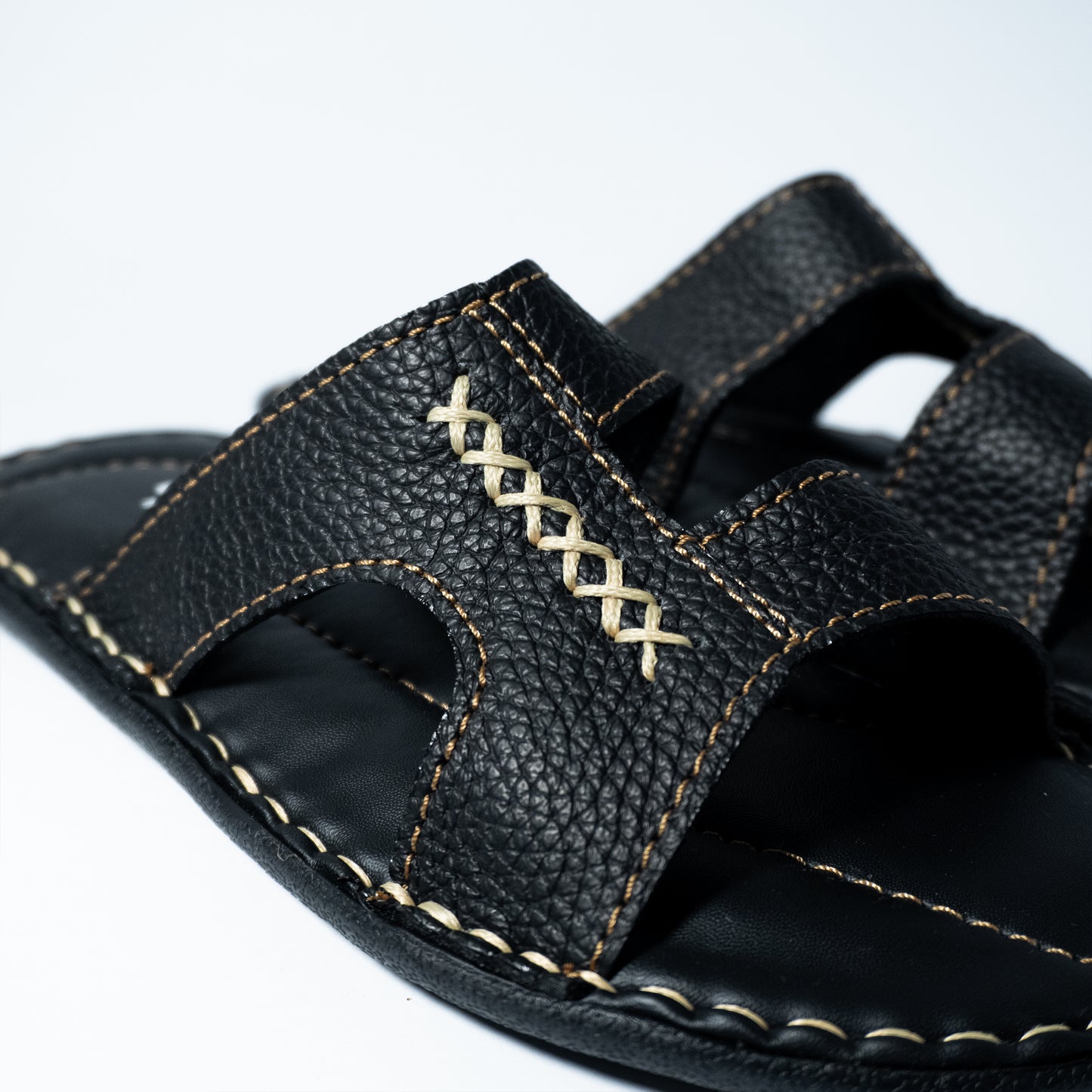 Black sandal with stitching on a white background