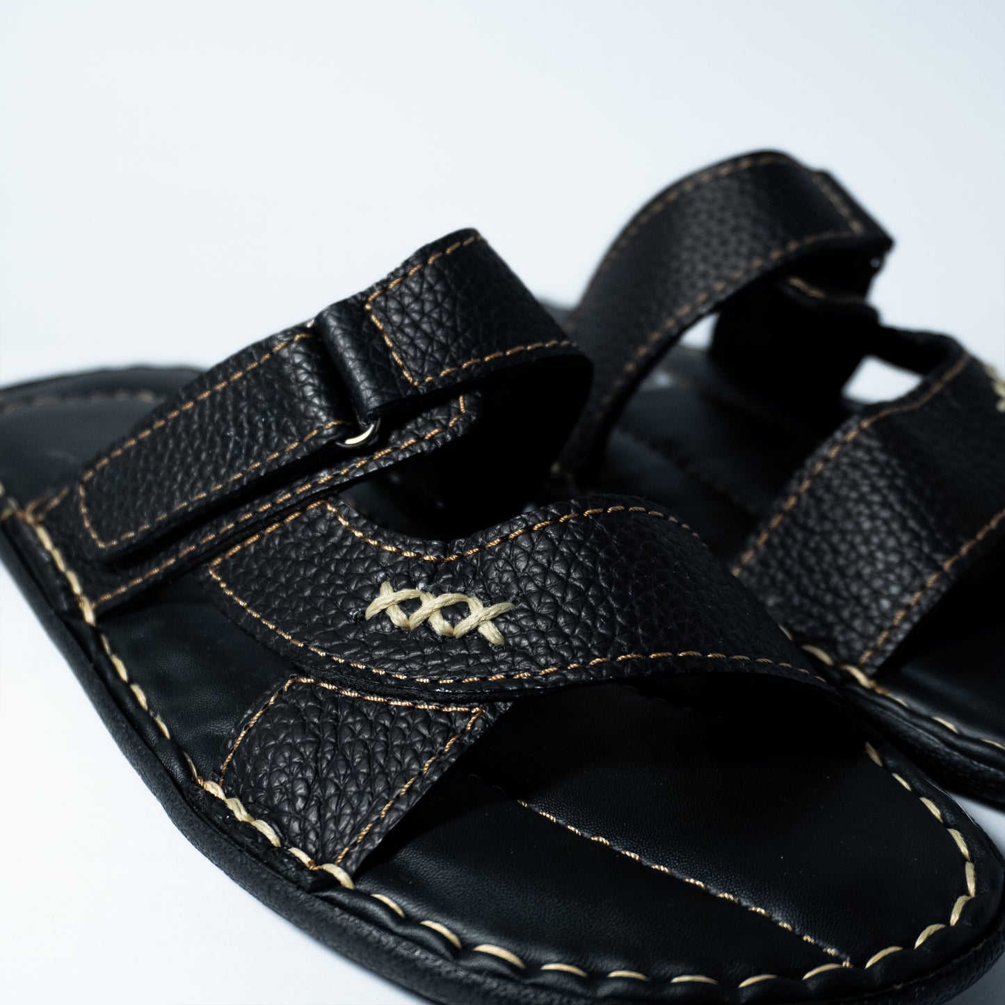 Black sandal with a strap and visible stitching on a white background