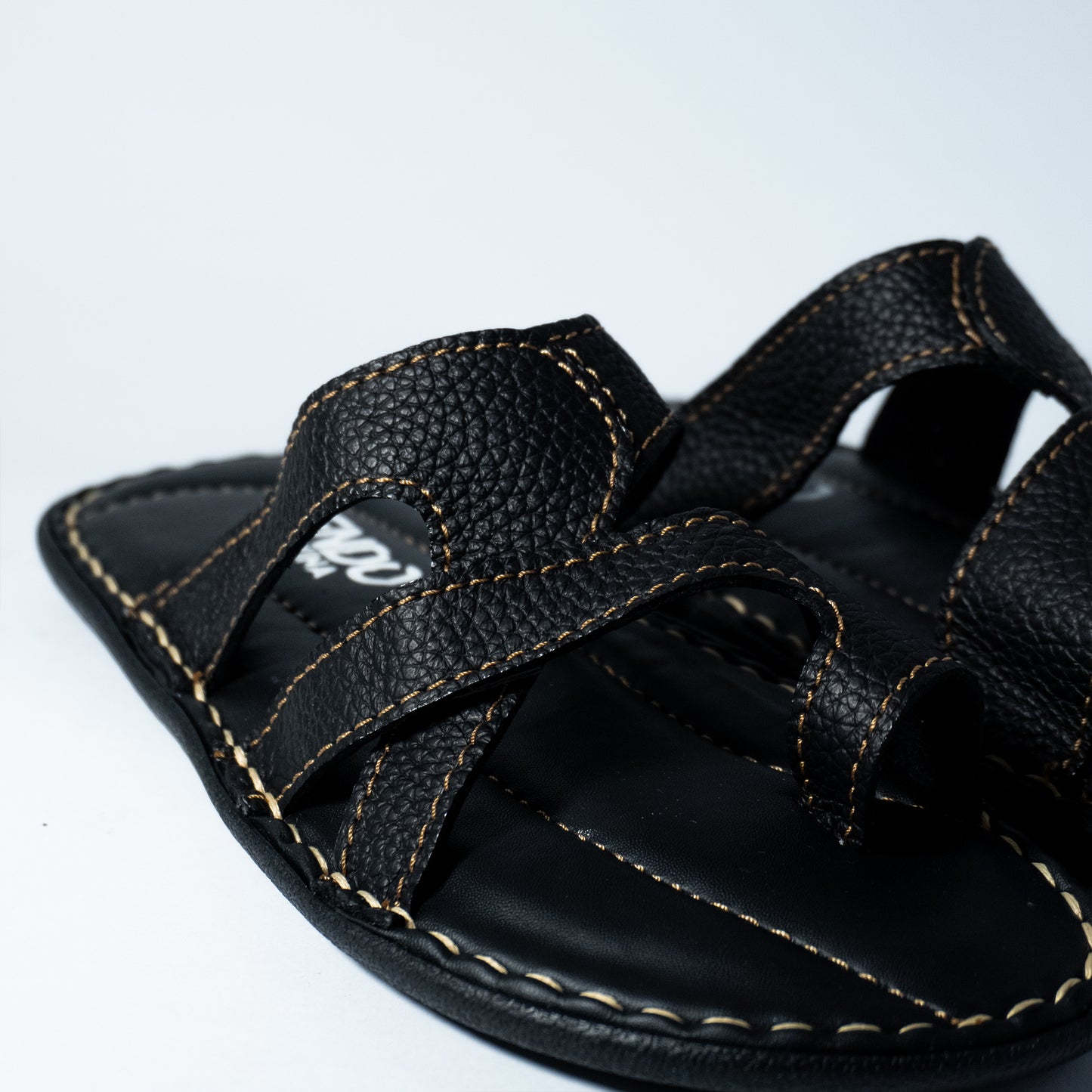 Black sandal with visible stitching on a white background