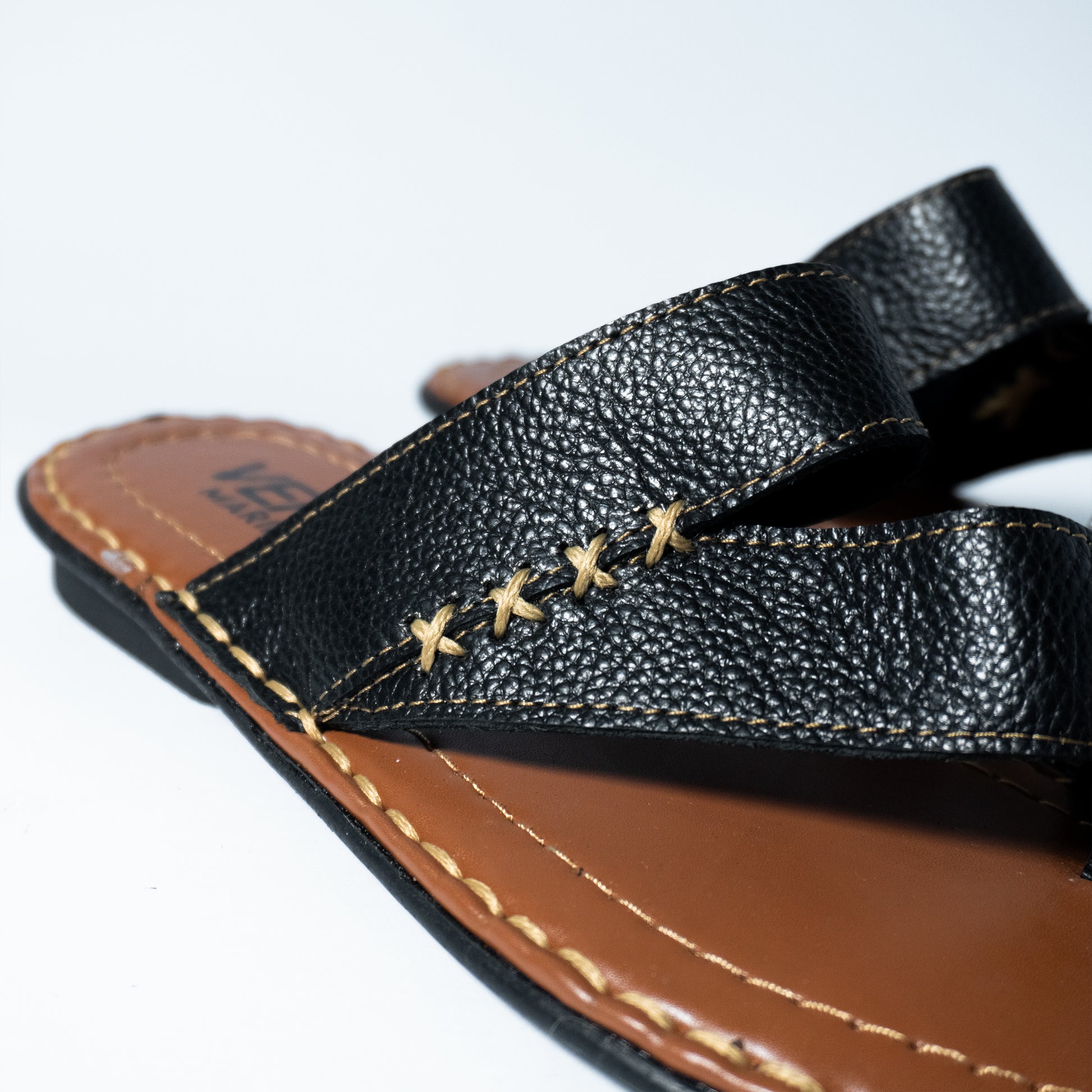 Close-up of a black sandal with brown sole on a white background