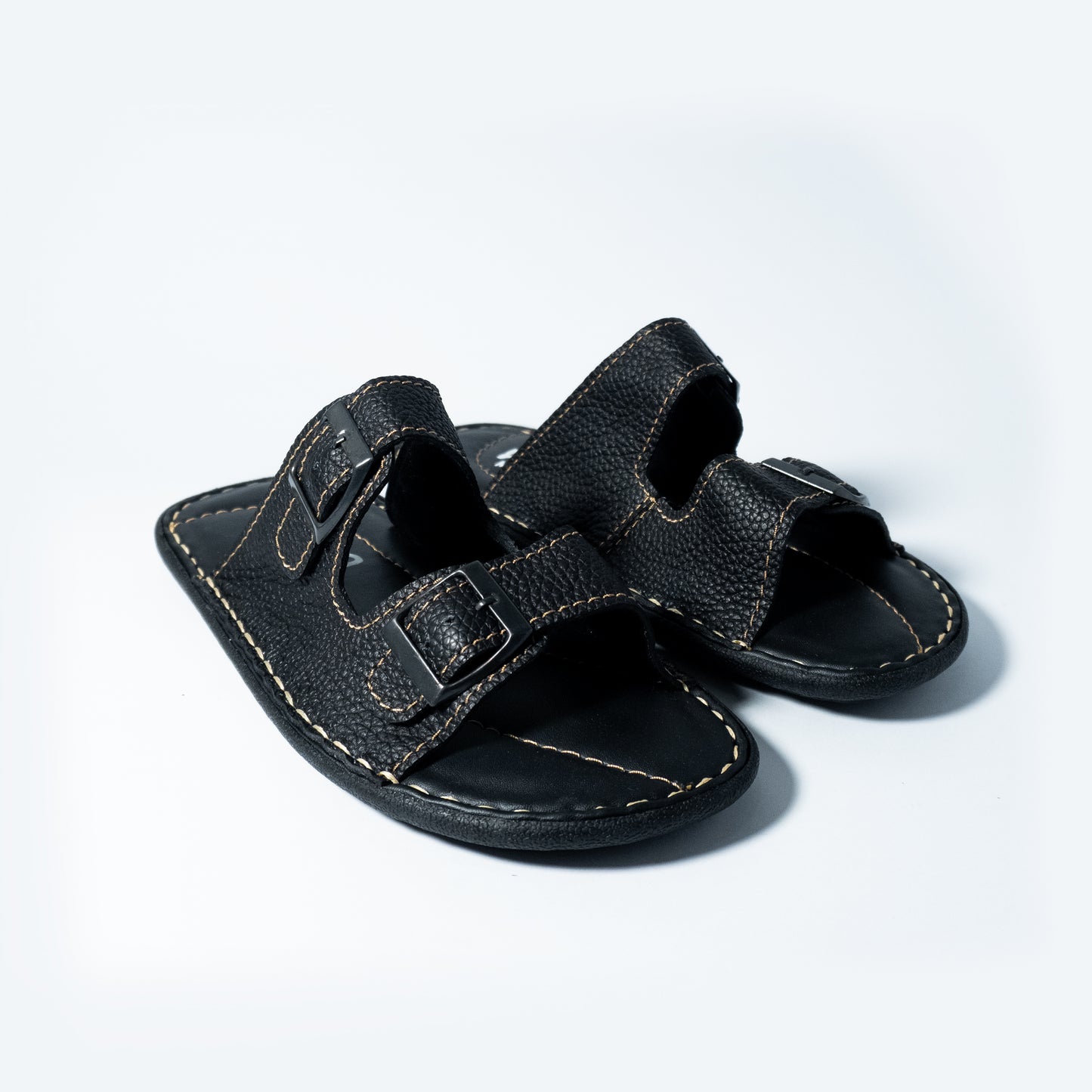 Pair of black leather sandals on a light gray background