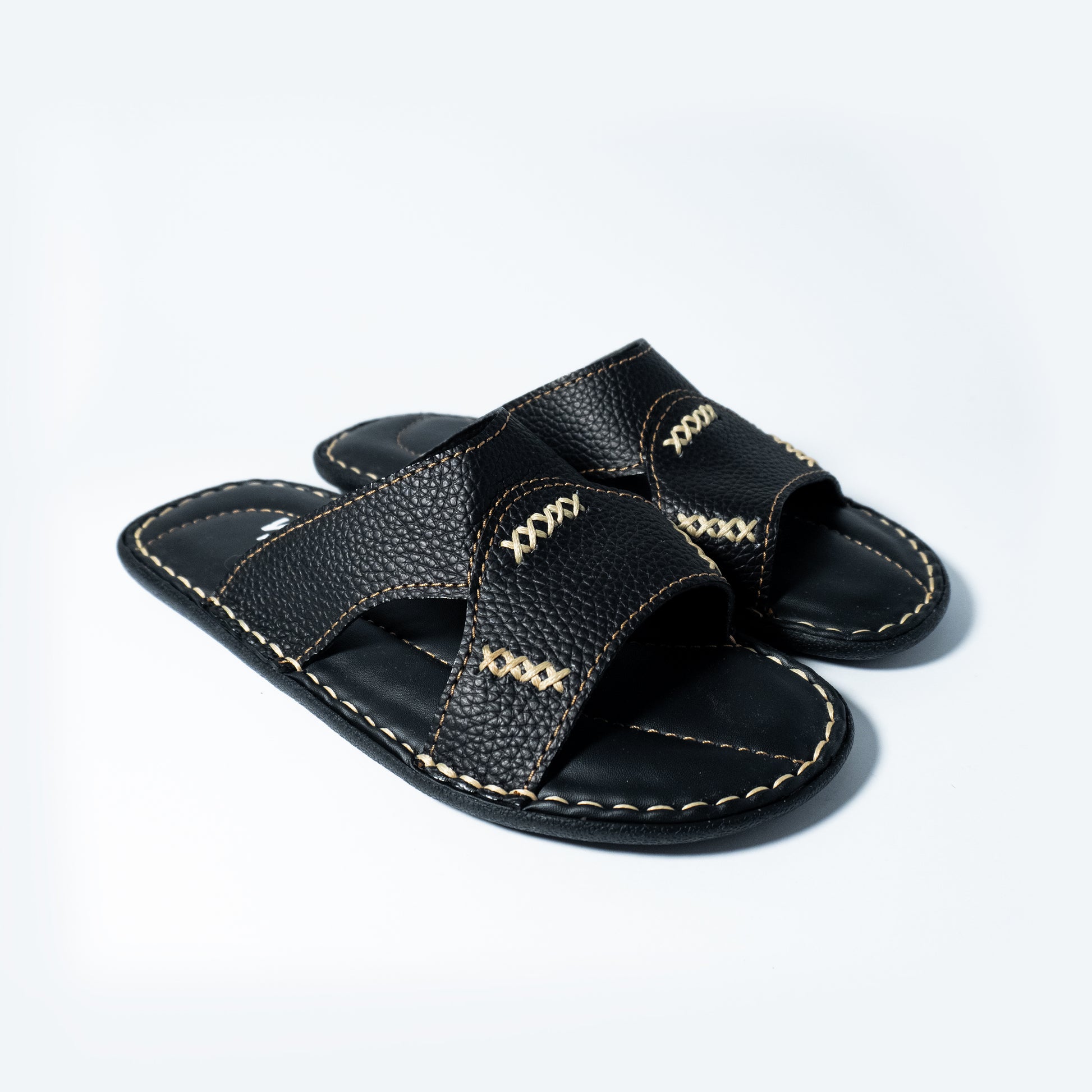 Pair of black sandals with stitching accents on a light gray background