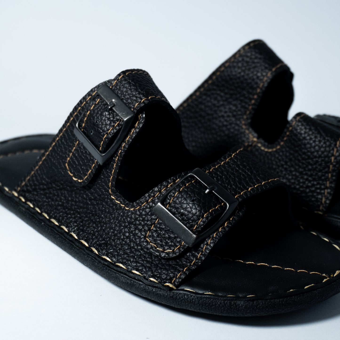 Black sandal with double buckle on a light gray background