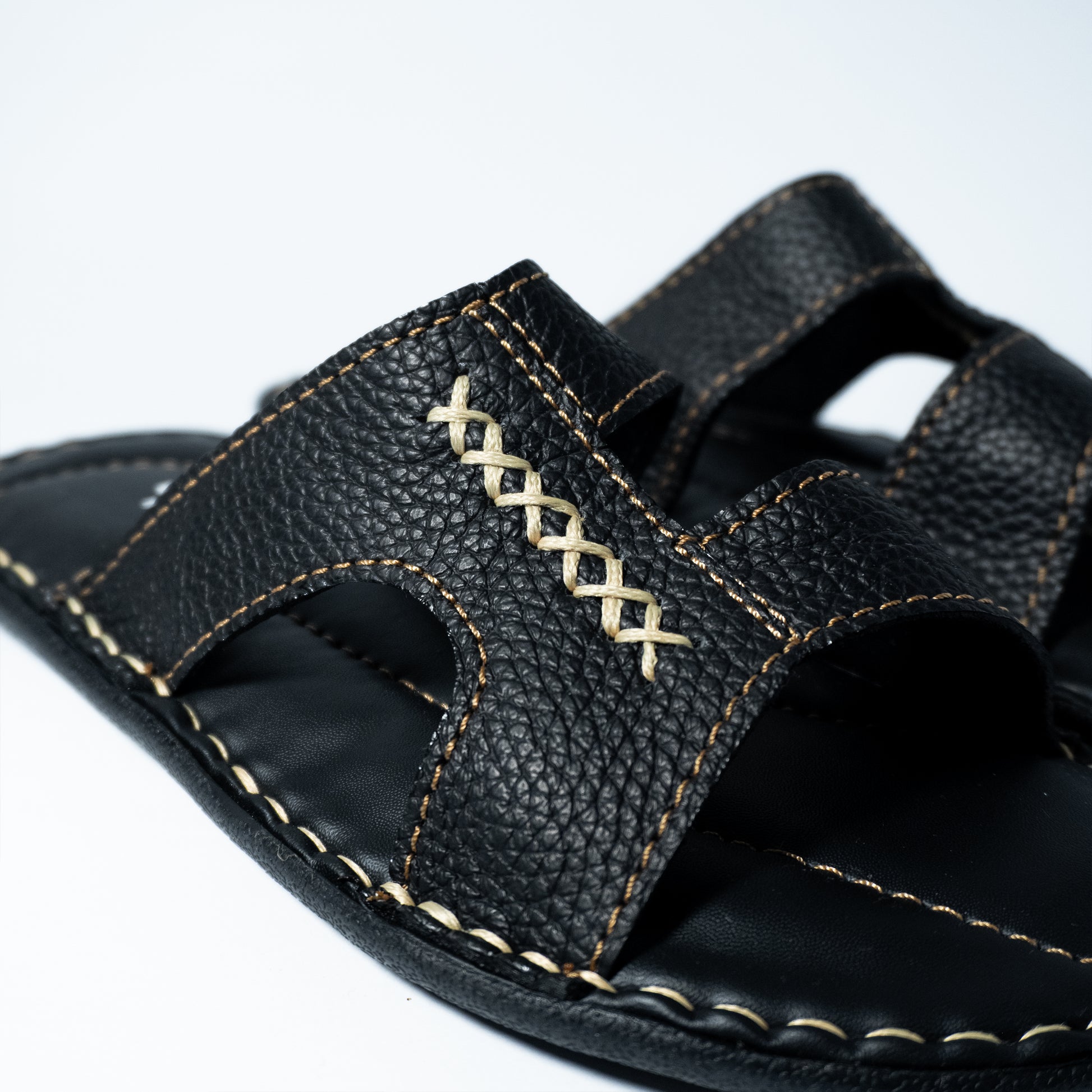 Black sandal with stitching on a white background