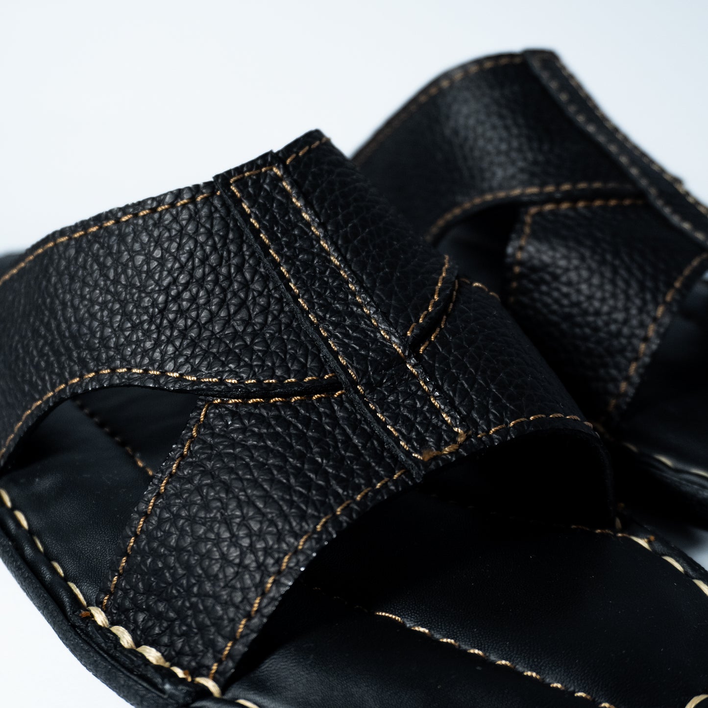 Close-up of black leather sandals with stitching detail on a white background
