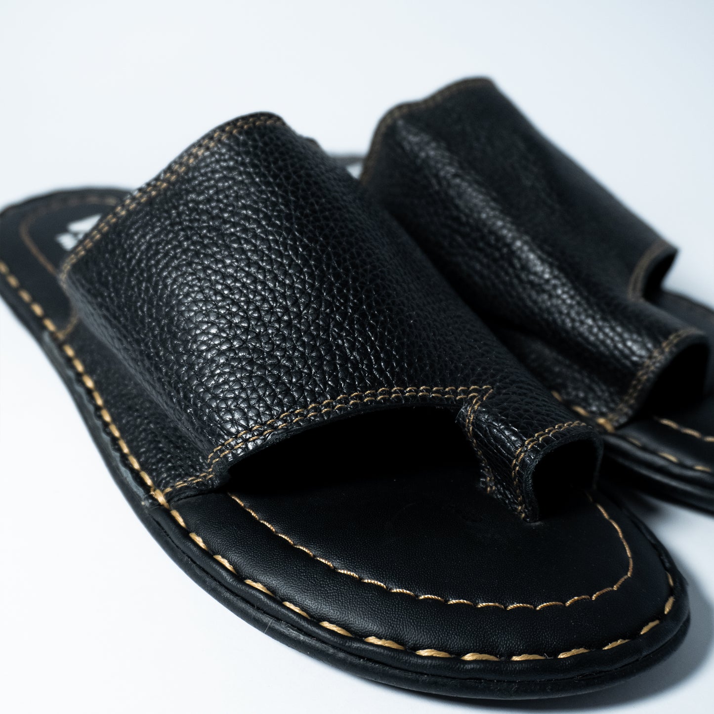 Close-up of a black sandal with leather strap on a white background