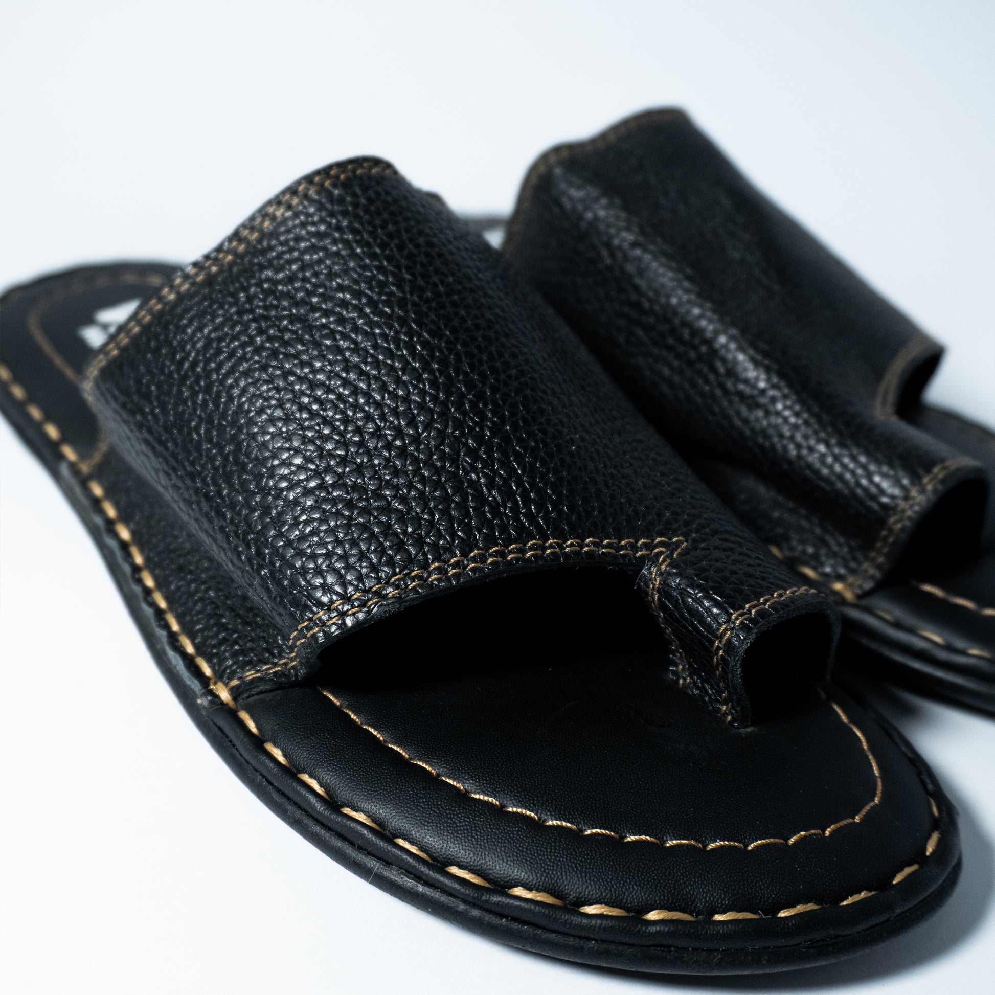 Close-up of a black sandal with leather strap on a white background