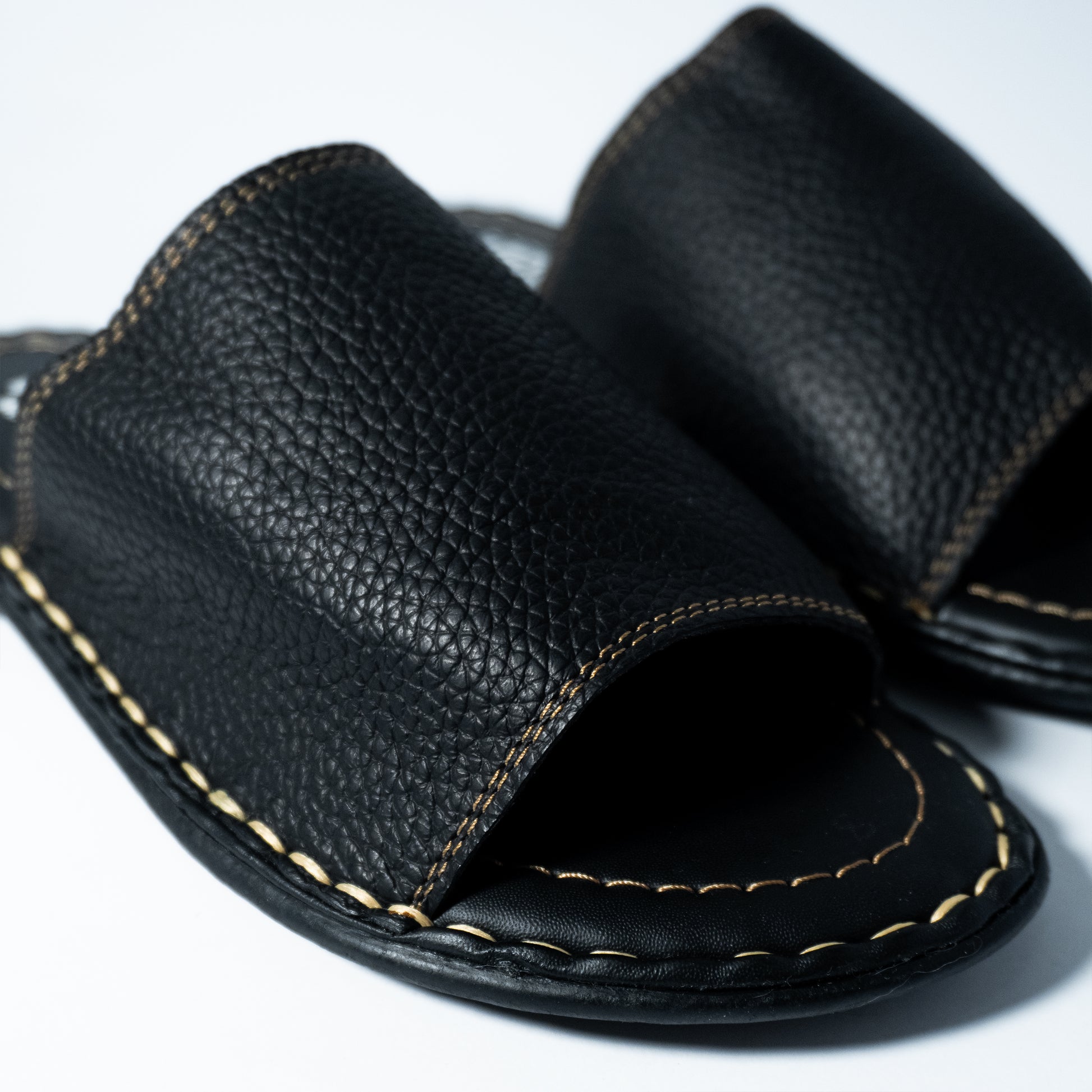 Pair of black leather sandals on a white background
