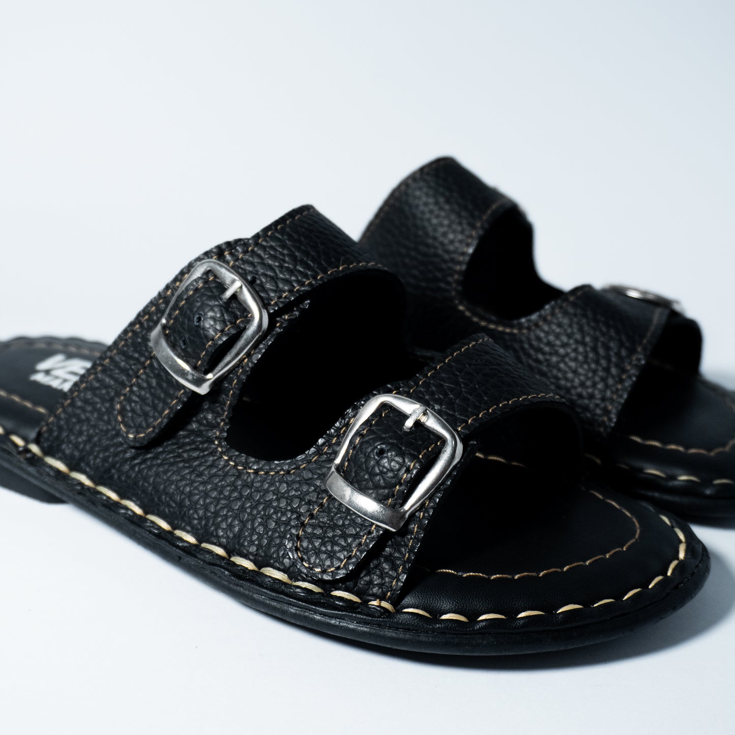 Black leather sandals with buckles on a light gray background