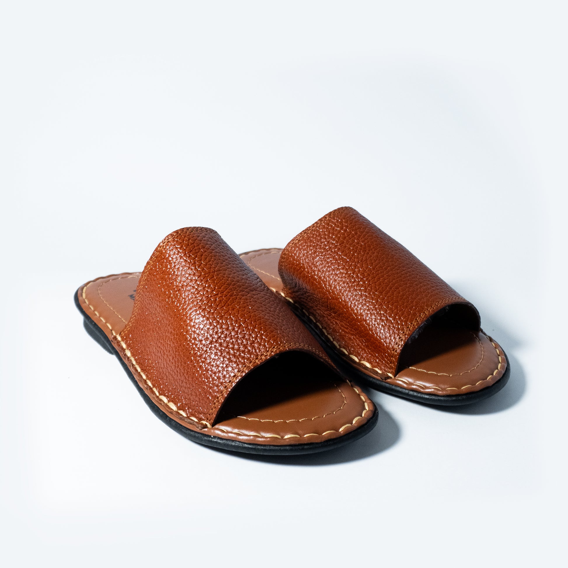 Pair of brown leather sandals on a light gray background