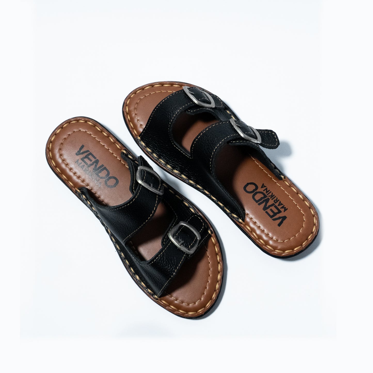 Pair of black sandals with brown soles on a white background