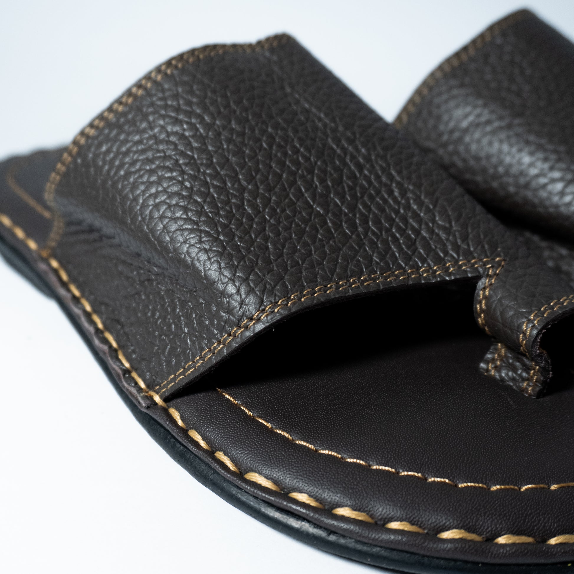 Close-up of a black leather sandal with visible stitching on a white background