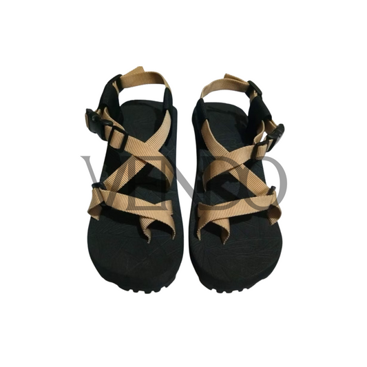 Black sandals with tan straps on a white background
